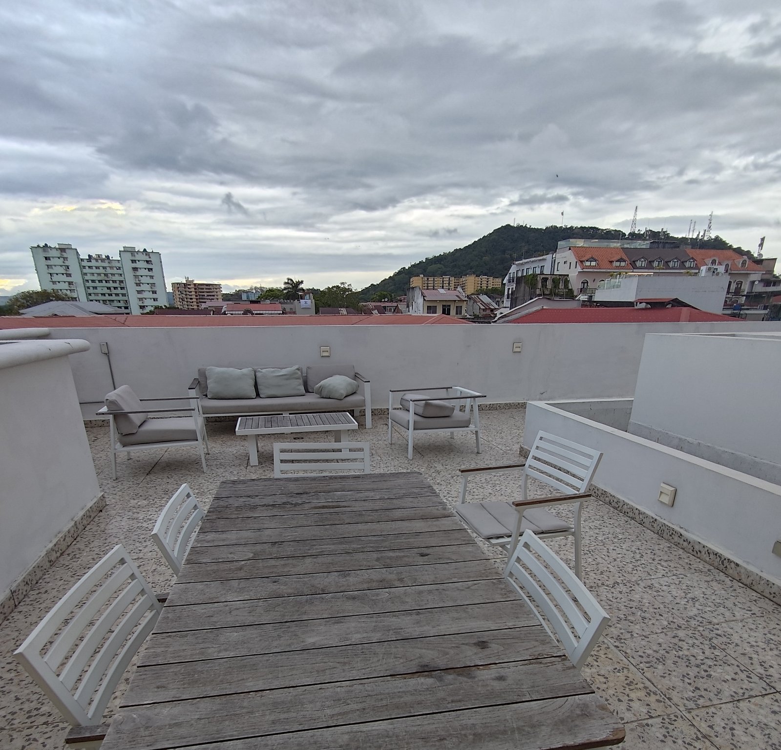 The rooftop terrace at the Casco Viejo apartment — wooden table, white chairs, lounge furniture in back.