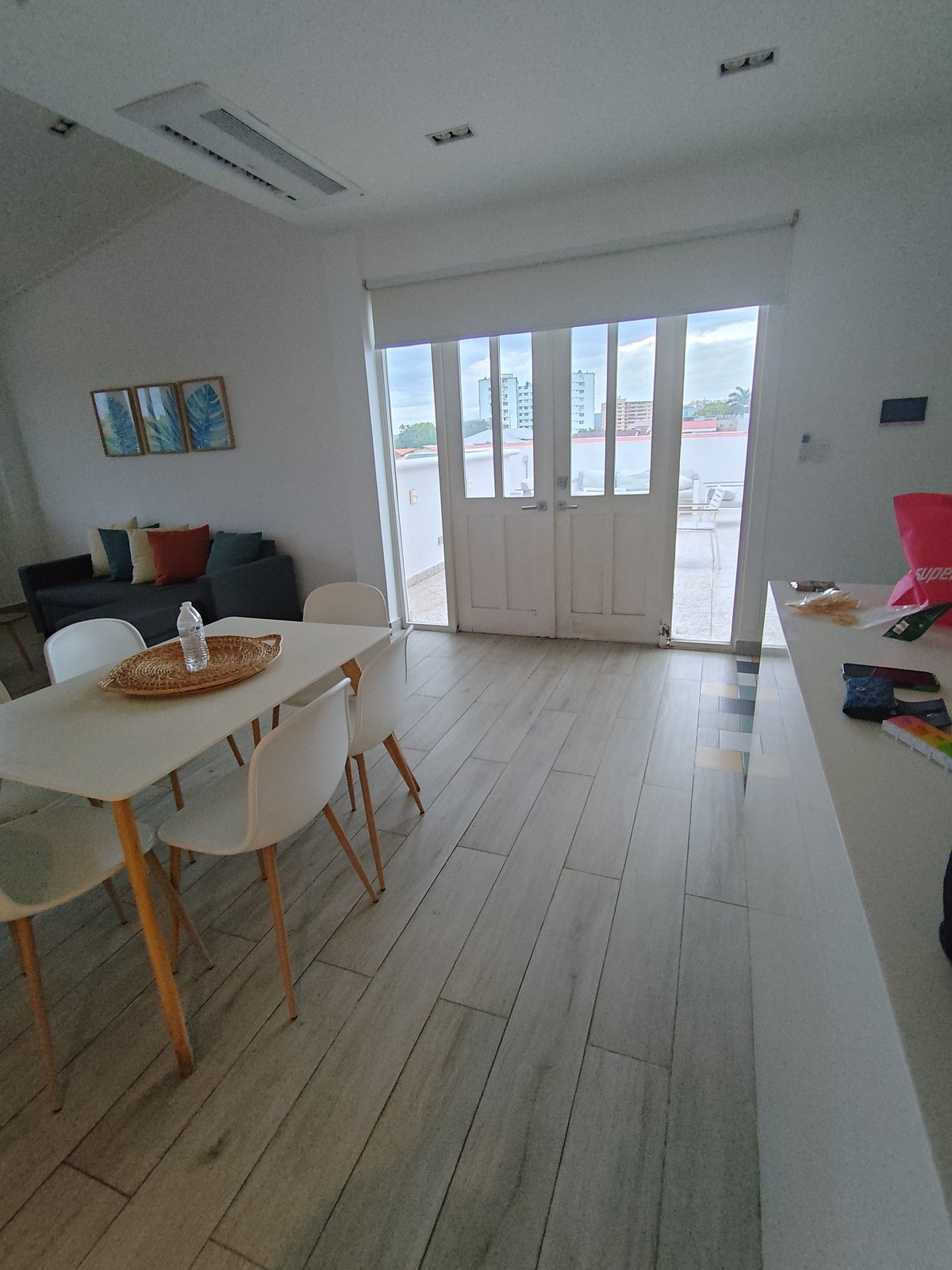 Interior of the Casco Viejo apartment — wood floors, dining table, sofa, kitchen counter, French doors leading to the rooftop.